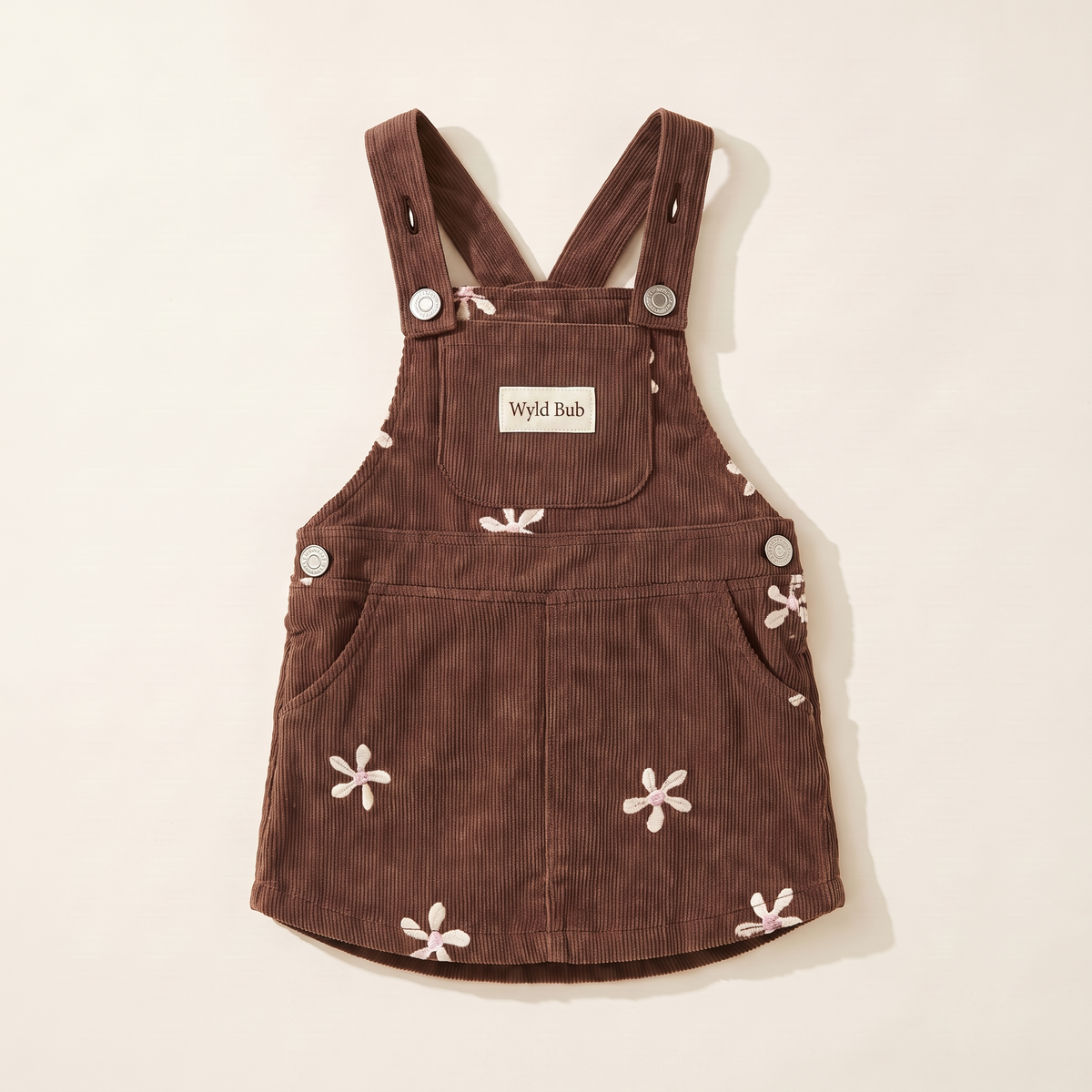 Flower corduroy baby pinafore dress in cocoa with cream and pink embroidered flowers, folded flat
