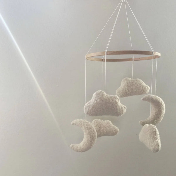 Decorative mobile with cloud and moon shapes hanging against a light gray background