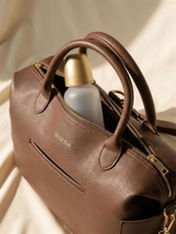Close-up of the gold Wyld Bub logo and zipper with a bottle inside the diaper bag