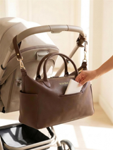 Wyld Bub diaper bag clipped to a pram with the magnetic front pocket in use