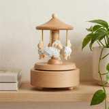 Wooden sheep carousel music box styled on a nursery shelf with linen books and a trailing plant