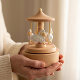 Hands cradling the 15cm beech wood sheep musical carousel to show its size