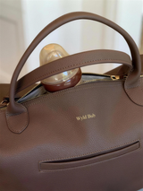 Close-up of the Wyld Bub Everyday Baby Bag top zip with a baby bottle inside