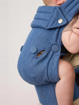 Close-up of baby seated in the Denim Blue carrier in the ergonomic M position