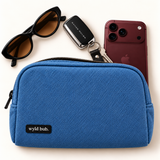 Wyld Bub denim blue pouch styled with a burgundy phone, keys and sunglasses